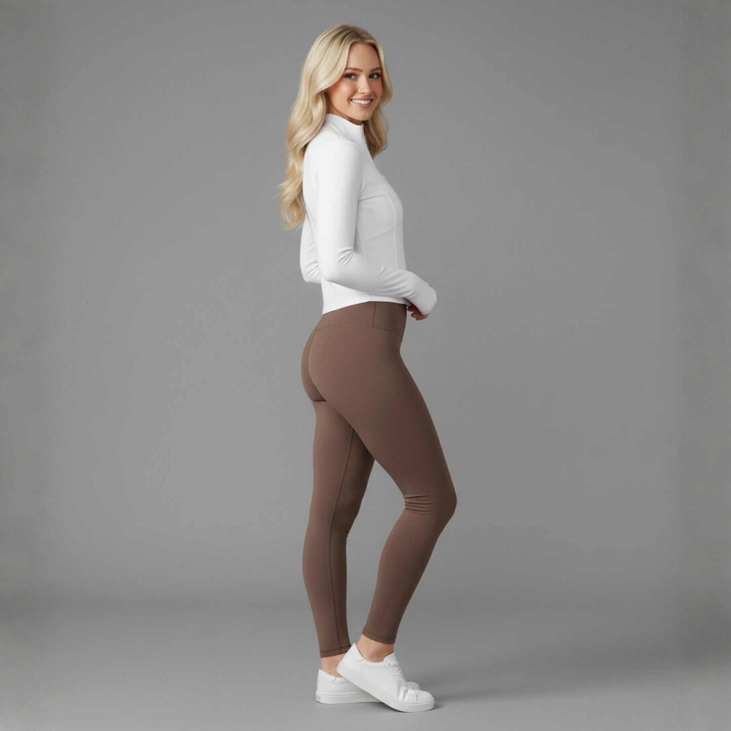 Woman wearing brown leggings and a white Dew Flex UPF50+ Performance jacket top on a gray background