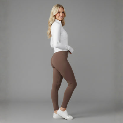 Woman wearing brown leggings and a white Dew Flex UPF50+ Performance jacket top on a gray background