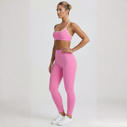Woman wearing a pink Dew elevate  sports bra and leggings set on a white background